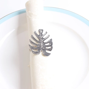 Détail du rond de serviette en feuille de monstera argentée sur dentelle blanche