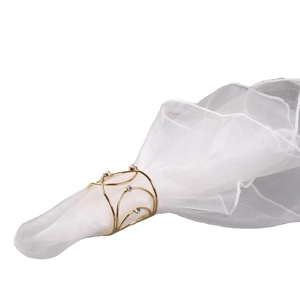 Golden woven wire napkin ring with diamond accents on white sheer fabric