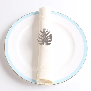 Détail d'un rond de serviette feuille de monstera argenté sur serviette blanche en tissu