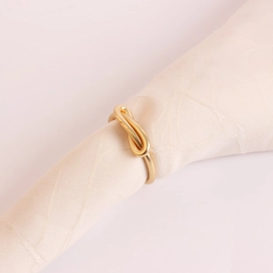Close-up of golden metal napkin ring with a minimalist bow knot on textured fabric