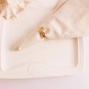 Elegant gold bow-tie metal napkin ring on white fabric for luxury table setting