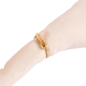 Elegant gold bow-tie metal napkin ring holder on pink silk fabric for table decor
