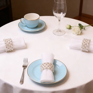 Detail of white pearl napkin rings with sparkling rhinestones on an elegant wedding table