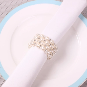 Close-up of four-row pearl napkin ring with rhinestones on a white linen napkin