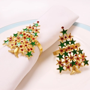 Détail de ronds de serviette sapin de Noël avec émail vert et strass rouges sur table