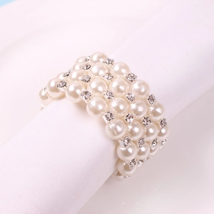 Elegant four-layer pearl and rhinestone napkin ring on a white linen napkin
