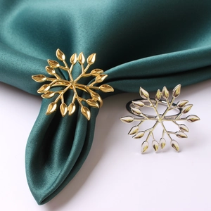 Detail of silver and gold snowflake napkin rings on silk fabric for festive table decor