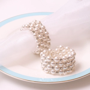 Elegant pearl and rhinestone napkin ring set on white porcelain plate for wedding decor