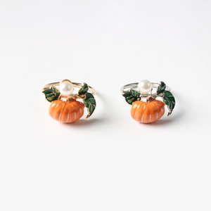 Close-up of pumpkin napkin rings with orange enamel leaves and white pearl accents