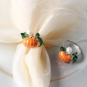 Detailed view of pumpkin napkin ring with orange enamel, green leaf, and pearl accent