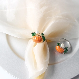 Detailed view of orange pumpkin napkin ring with green enamel leaf and white faux pearl decoration