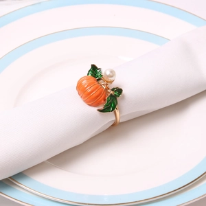 Orange pumpkin napkin ring with green leaf and pearl detail on white ceramic plate