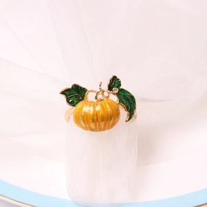 Close-up of a pumpkin napkin ring with orange enamel detail on a white fabric base