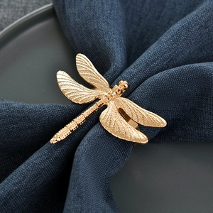 Elegant gold dragonfly napkin ring with detailed wings on a navy blue linen napkin