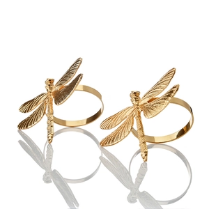 Close-up of golden dragonfly napkin rings with detailed wings and a polished finish