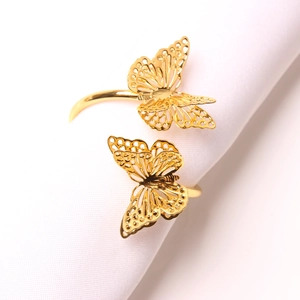 Eleganter goldener Schmetterlings-Serviettenring mit filigranen Flügeln auf Stoff
