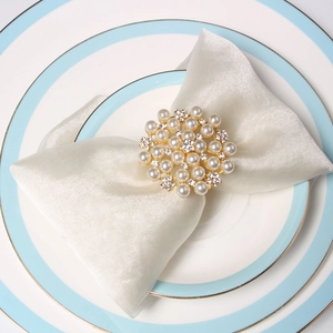 Elegant gold pearl napkin ring with crystal rhinestones on a white fabric dinner napkin