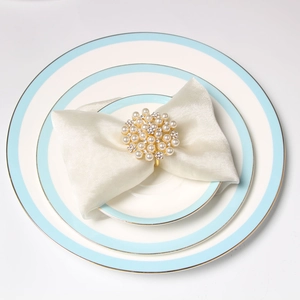 Detailed view of a gold floral napkin ring with pearls and rhinestones on a satin napkin