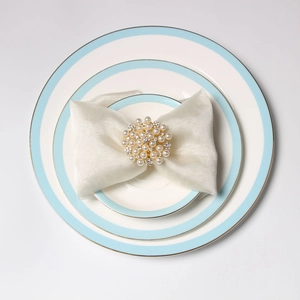 Close-up of elegant pearl cluster napkin ring on beige tulle over ceramic plates