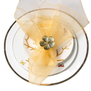 Portatovagliolo a fiore dorato con tessuto delicato su piatto di porcellana elegante