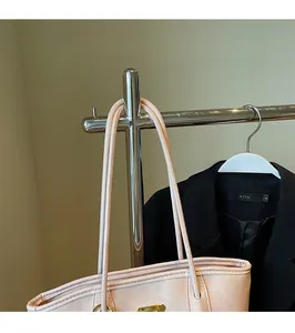 Détail d'un sac cabas beige rose avec boucle dorée suspendu à un support métal