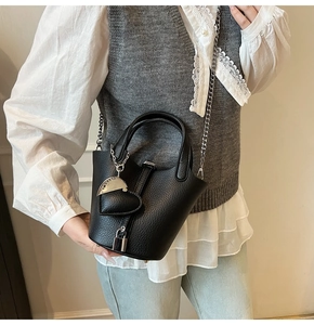 Detail of black pebbled leather bucket bag with silver chain strap and heart charm