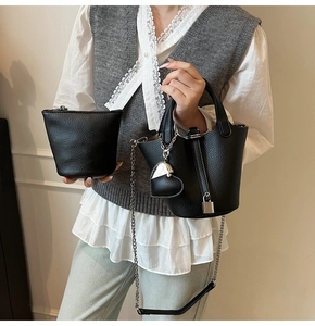 Detail of black lychee grain leather bucket bag set with silver chain and heart charm
