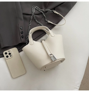Detail of off-white lychee leather bucket bag with silver padlock and chain strap