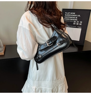 Détail du sac croissant Y2K noir avec boucles argentées et sangles à œillets sur modèle