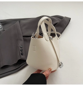 Detail of white lychee leather bucket bag showing silver padlock and fine stitching