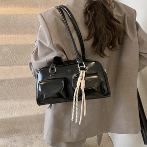 Glossy black patent leather shoulder bag with dual buckled pockets and star pendant charm