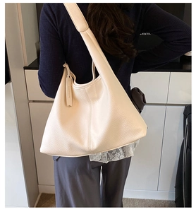 Close-up of beige litchi grain leather tote bag showing texture and wide shoulder strap