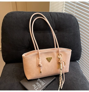 Gros plan du sac cabas en cuir rose avec logo triangle doré sur chaise en velours noir