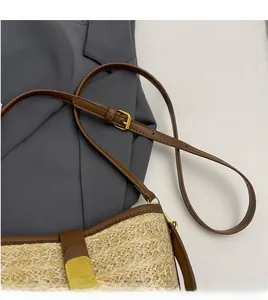 Detail of hand-woven straw bag featuring dark brown leather trim and golden metal buckle