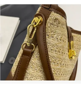 Close-up of golden metal hardware and brown leather trim on woven straw bucket bag