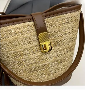 Detailed macro view of woven straw bucket bag with golden textured wave twist lock