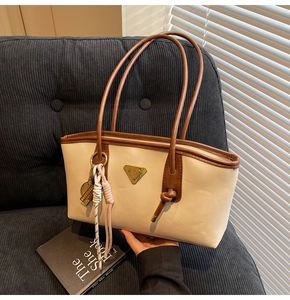 Détail du sac cabas beige et marron avec plaque en métal et pendentif tressé décoratif