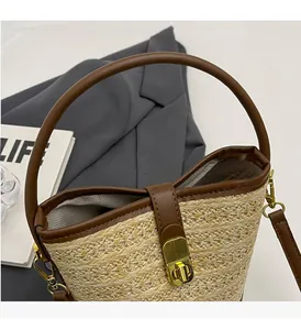 Detail of woven straw bucket bag with brown leather trim and golden metal swivel lock