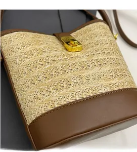 Detail of straw and brown leather bucket bag with a golden metal twist-lock buckle