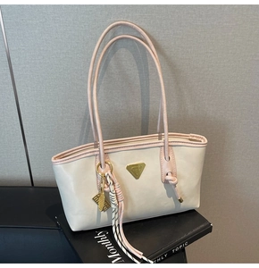 Détail du sac cabas blanc avec bordure rose, logo triangle et breloque raquette de tennis