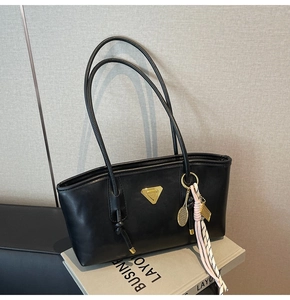 Détail du sac cabas en cuir noir avec plaque dorée et accessoire pendentif raquette de tennis