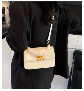 Detail of a beige polished leather handbag with woven handle and gold rivet lock