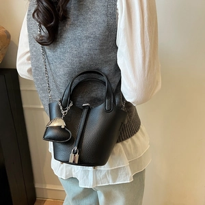 Chic black litchi leather bucket bag with silver chain strap shown on a model