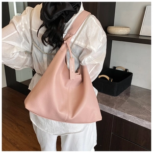 Close-up of pink litchi grain leather bucket bag showing soft texture and shoulder strap