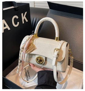 Détails d'un sac en cuir crème avec garnitures dorées, pendentif boulier et foulard