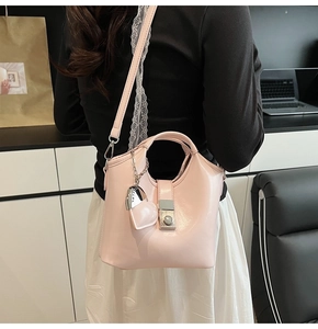 Detalle de bolso tipo cubo rosa claro con colgante de corazón y correa ajustable