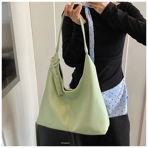 Detail of light green litchi texture leather hobo bag with designer tag on shoulder