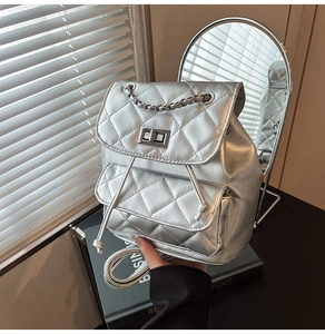 Detail of silver quilted leather mini backpack with metal chain and turn-lock closure