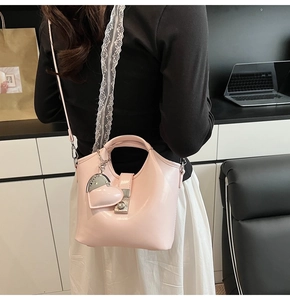 Detailansicht der rosa Beuteltasche mit Herzanhänger zeigt Textur und Schultergurt