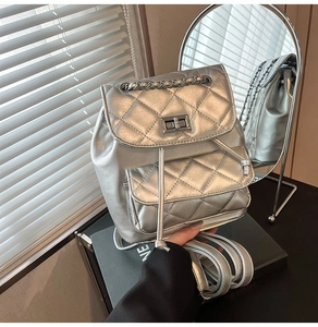 Close-up of quilted silver mini backpack with metallic finish and metal chain details